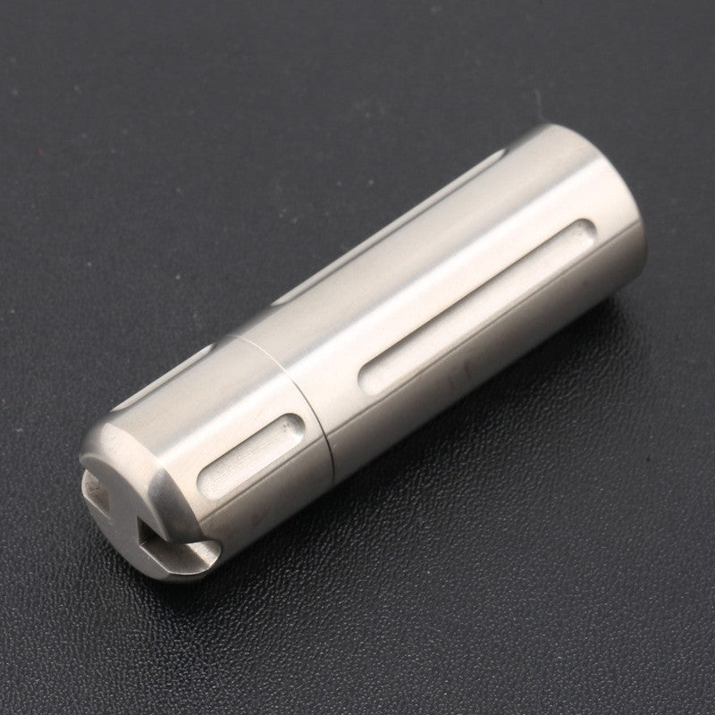 Compact titanium pill box shown next to black gift box packaging
