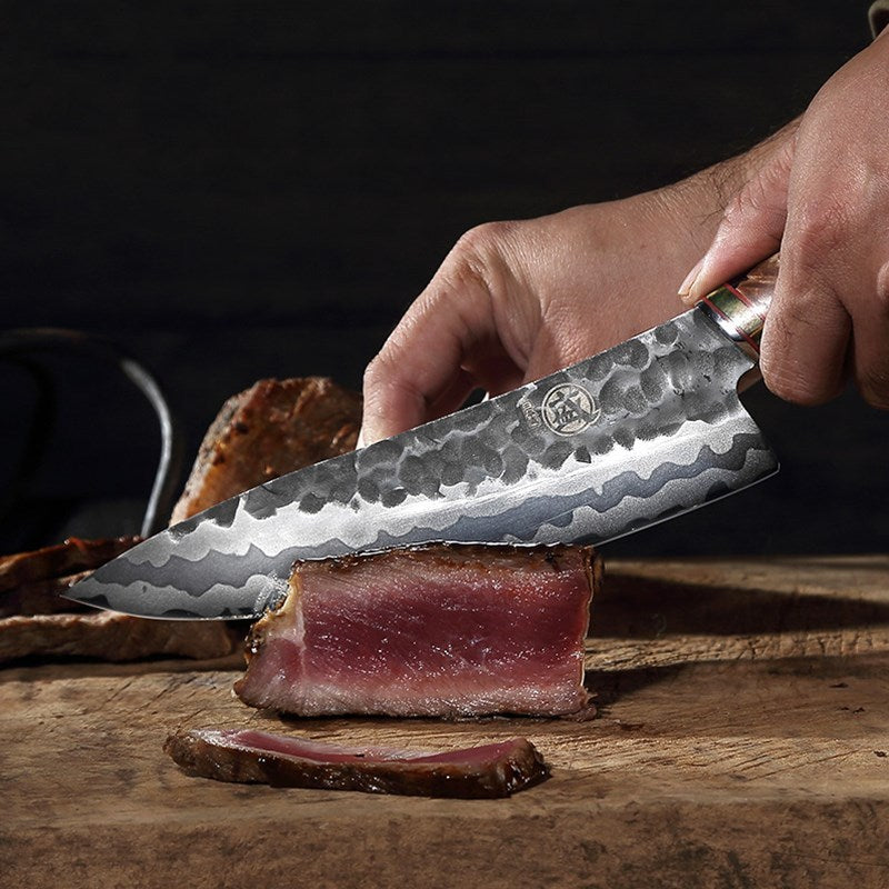 Damascus steel knife slicing through meat with precision on a wooden surface.