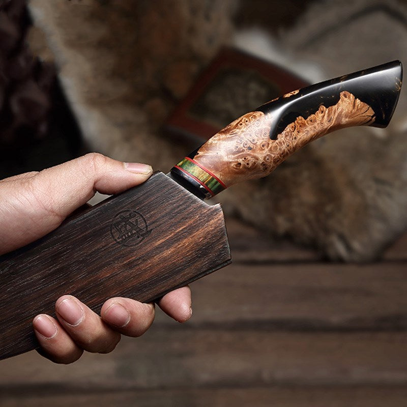 Damascus steel knife held by a man’s hand with a firm grip, placed in its wooden sheath.