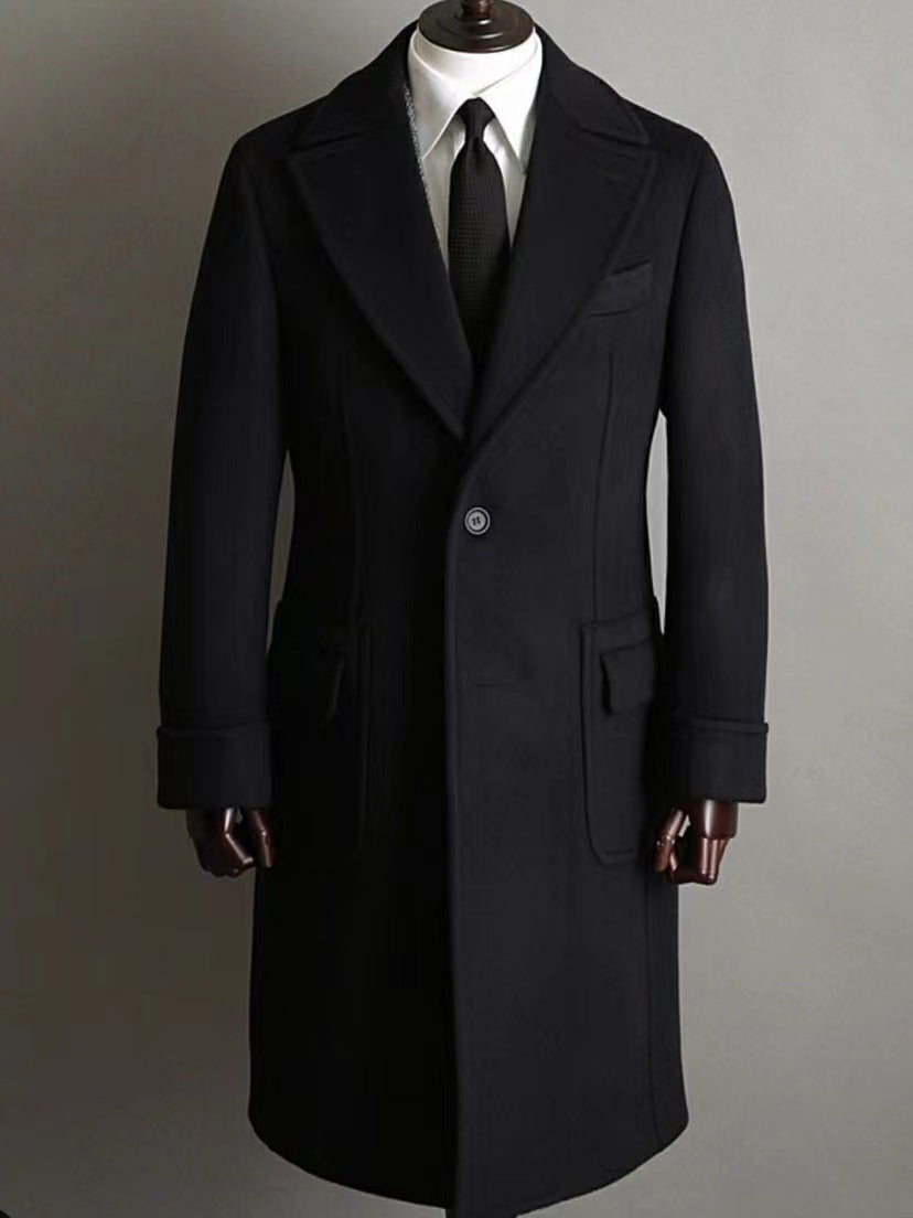 Black double breasted men’s coat on hanger showing cut and texture