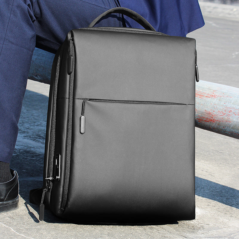 Sleek black anti-splash backpack placed next to a seated man, perfect for business or study.