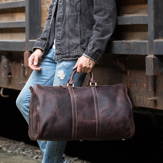 Authentic genuine cowhide travel bag carried by a rugged figure in a western setting near a train.